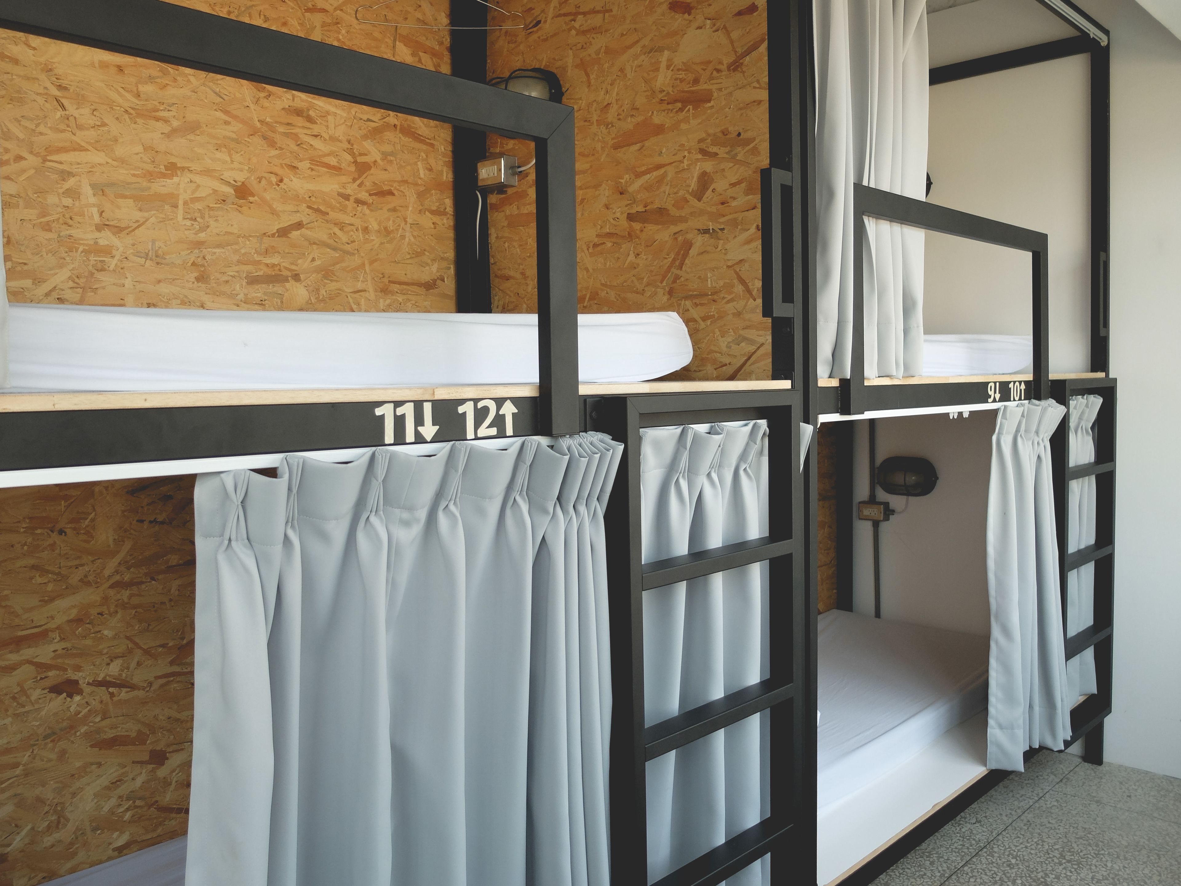 A bunk bed room with a wooden wall, numbered beds, and curtains.