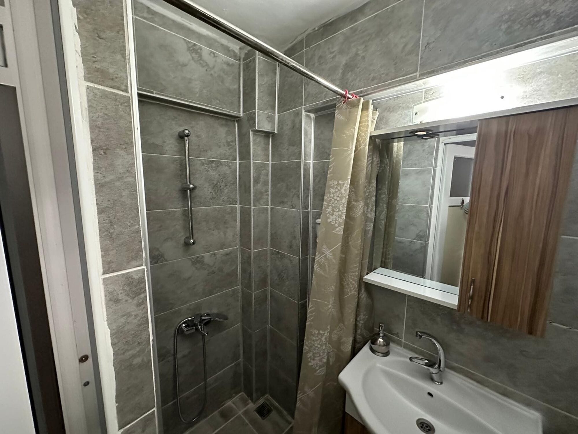 A bathroom with a shower, sink, and mirror.