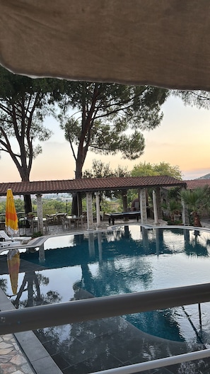 Una piscina al aire libre, sombrillas, sillones reclinables de piscina
