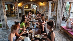 A group of people dining at an outdoor restaurant with stone flooring and ornate columns. - Atilla's Getaway (Selçuk)