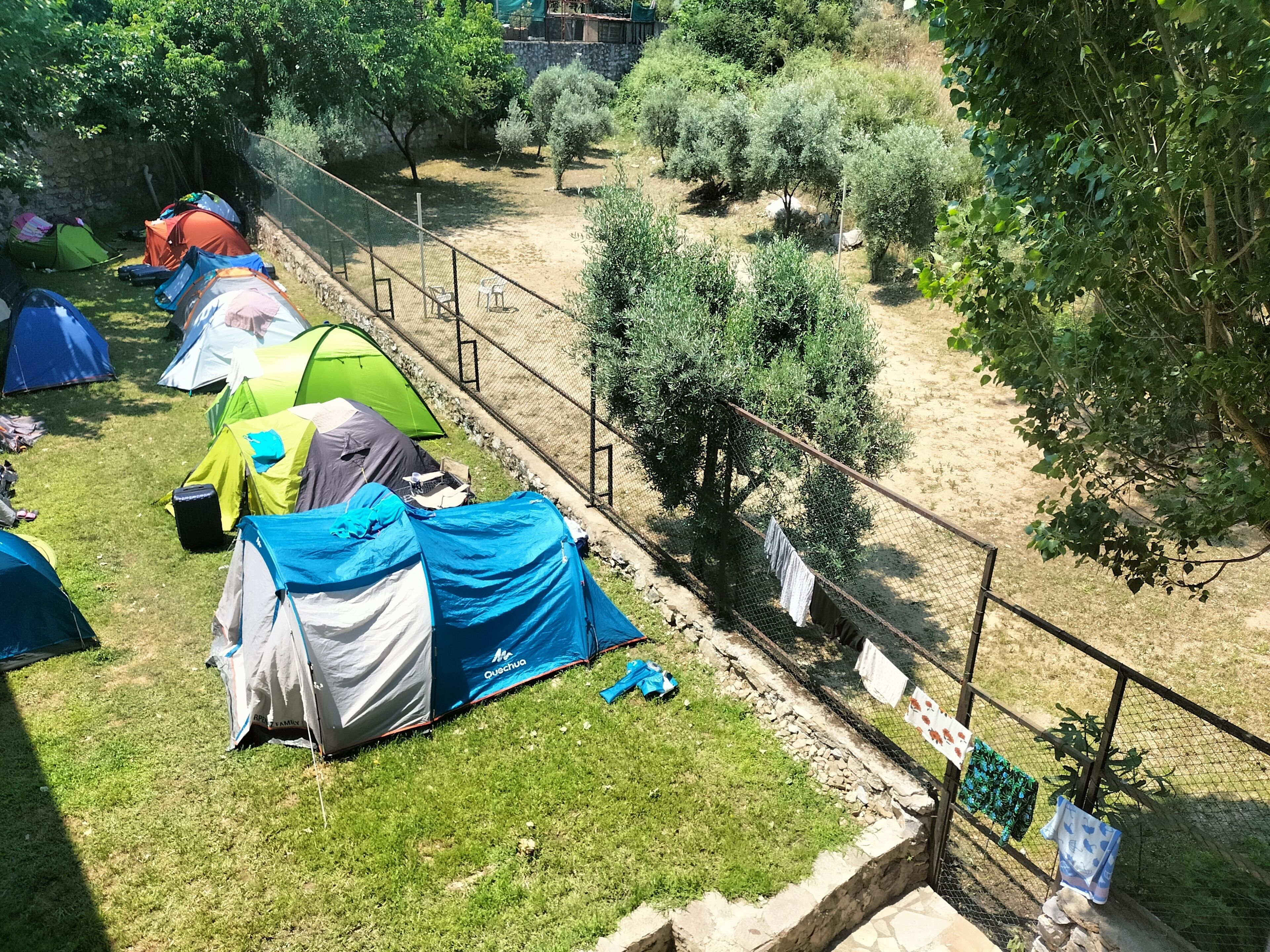 Un camping con varias tiendas de campaña y una zona delimitada por una valla.