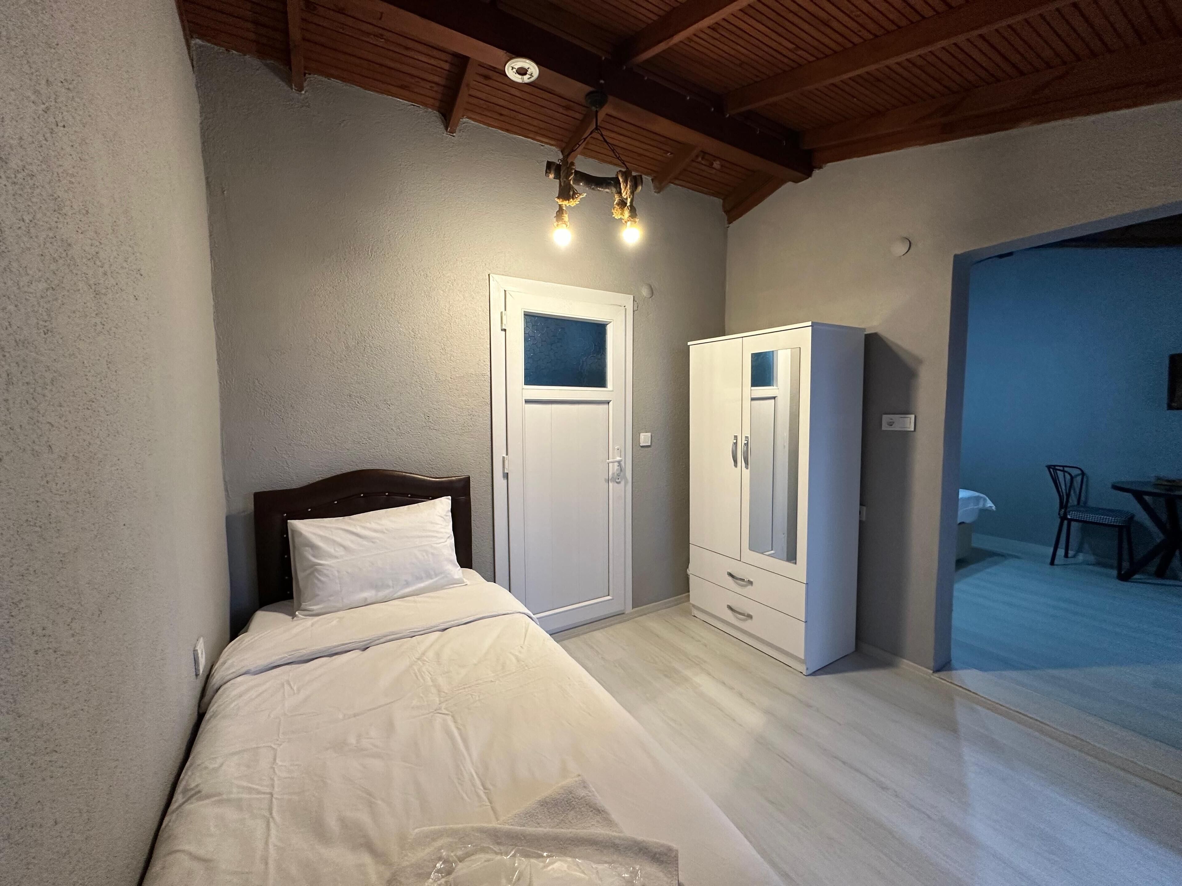 Een slaapkamer met een bed, een kledingkast, een deur en een klein tafeltje met stoelen.