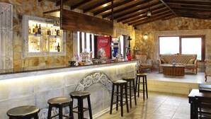 A bar area with a stone wall, wooden ceiling, and bar stools. - Atilla's Getaway (Selçuk)