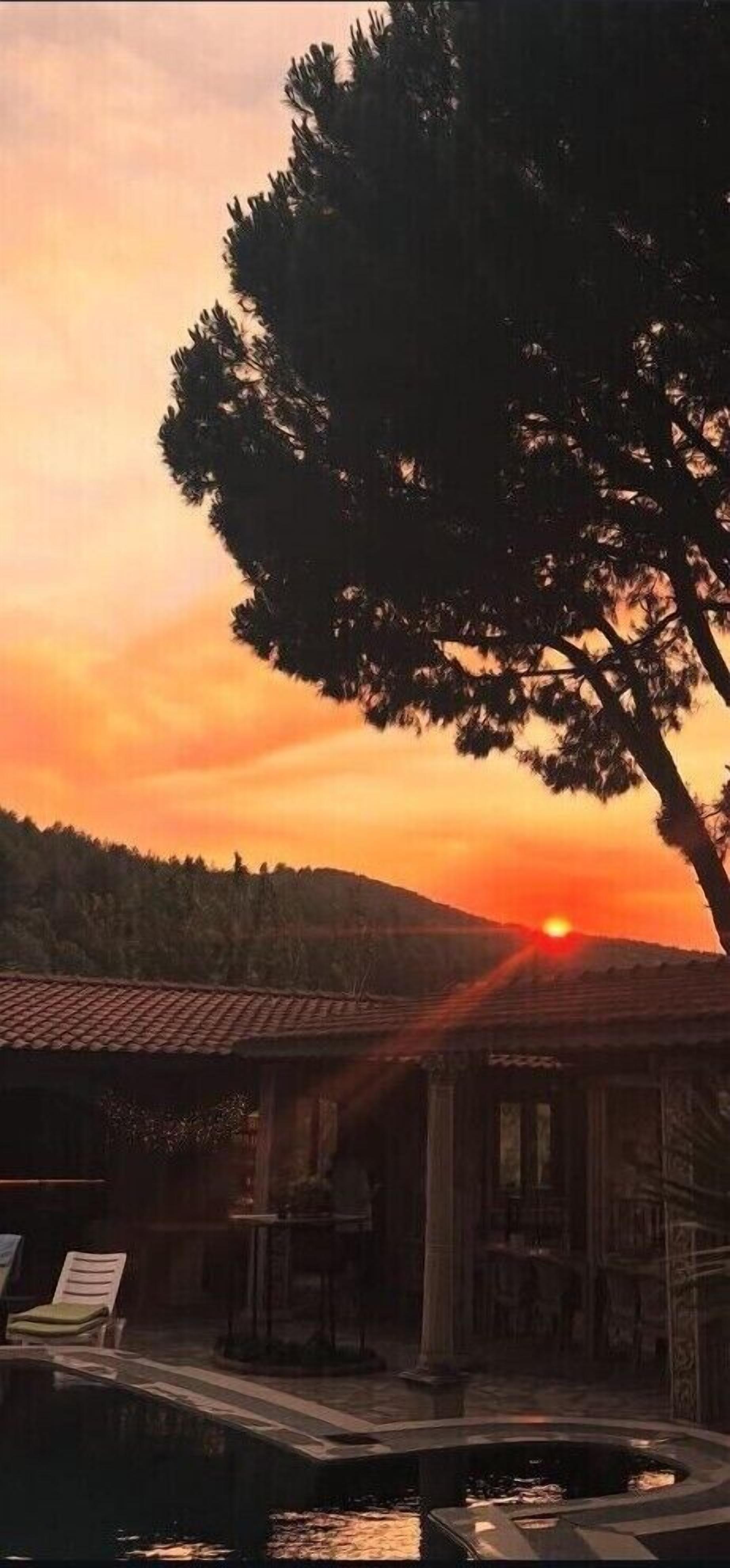 Vista al atardecer con una piscina y un edificio de techo a tejas.
