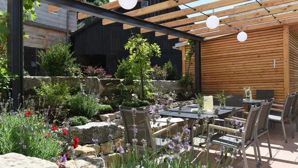 An outdoor patio with stone walls, wooden pergola, and seating area. - Hotel Gasthof Hereth (Wirsberg)