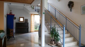A spacious living area with a staircase, a fireplace, and a large window. - Hotel Gasthof Hereth (Wirsberg)