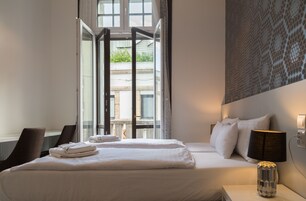 Hotellihuone, jossa on suuri sänky, työpöytä ja näkymä avoimesta ovesta.