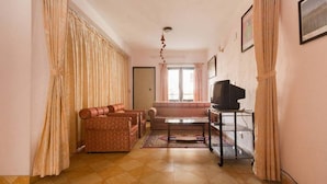 A living room with a sofa, a coffee table, and a TV on a stand. - Le Rhododendron Chambres D'hotes (Kathmandu)