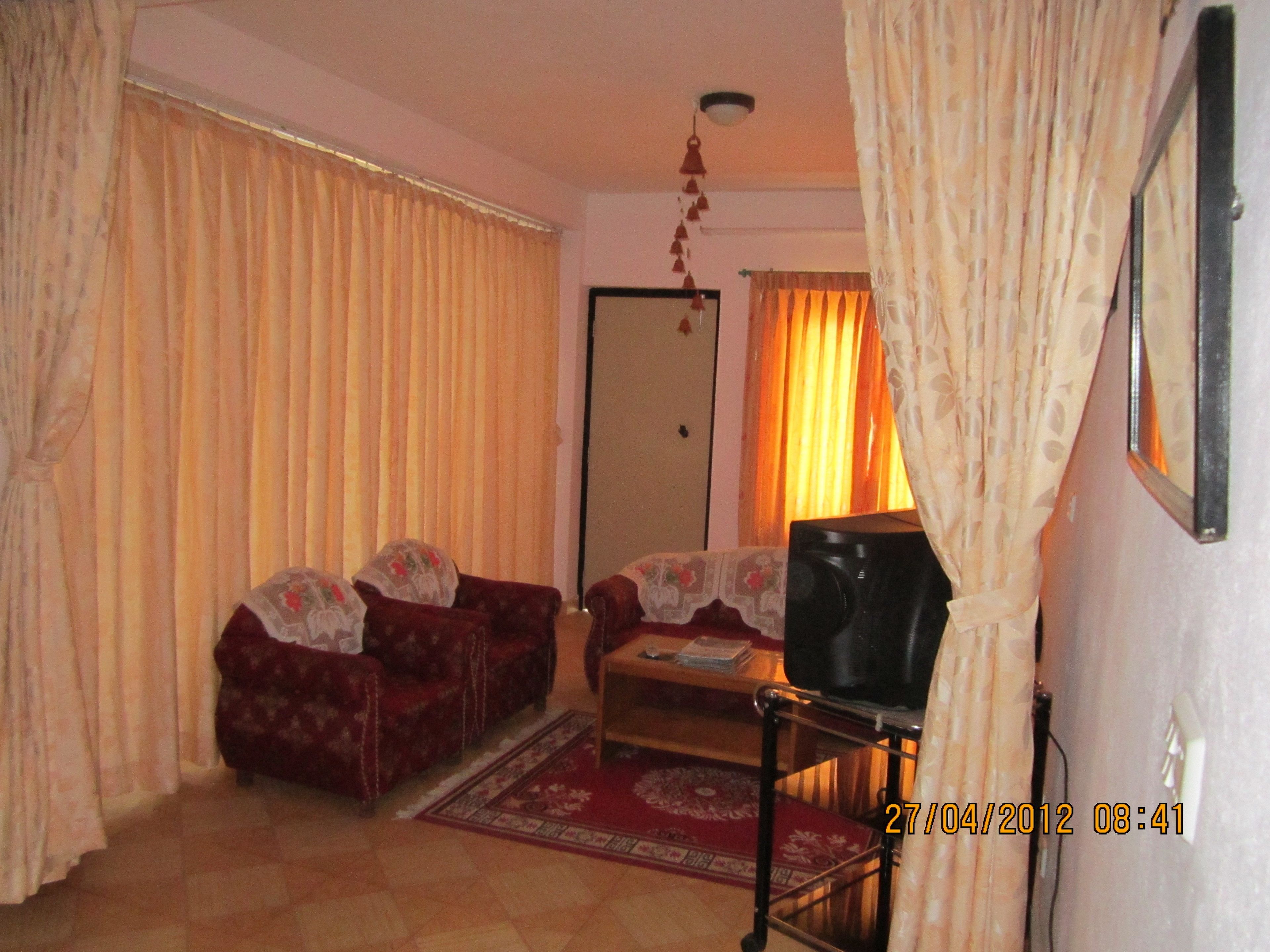 A living room with two sofas, a television on a stand, and a door with curtains.