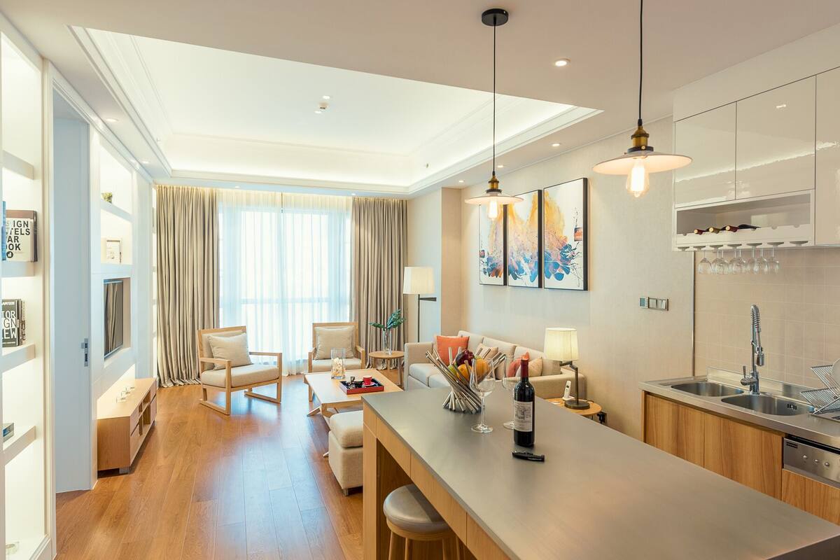 A modern kitchen with a bar area, wooden flooring, and a dining set.