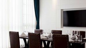 A conference room with a long table, several chairs, and a flat-screen TV on the wall.