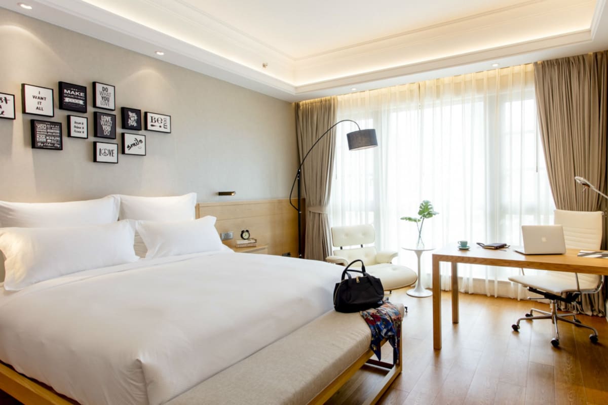 Una habitación de hotel con una cama grande, un escritorio con una computadora portátil, una silla y un televisor.