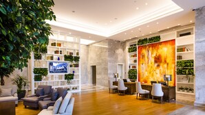 A modern lobby with a wooden floor, a seating area with sofas and chairs, a large bookshelf, and a TV mounted on the wall. - Residence G Shenzhen (Shenzhen)