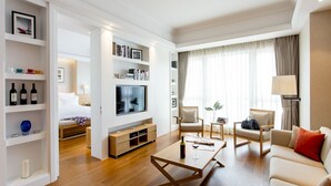 A modern living room with a sofa, coffee table, TV, and shelves with books and decorative items. - Residence G Shenzhen (Shenzhen)