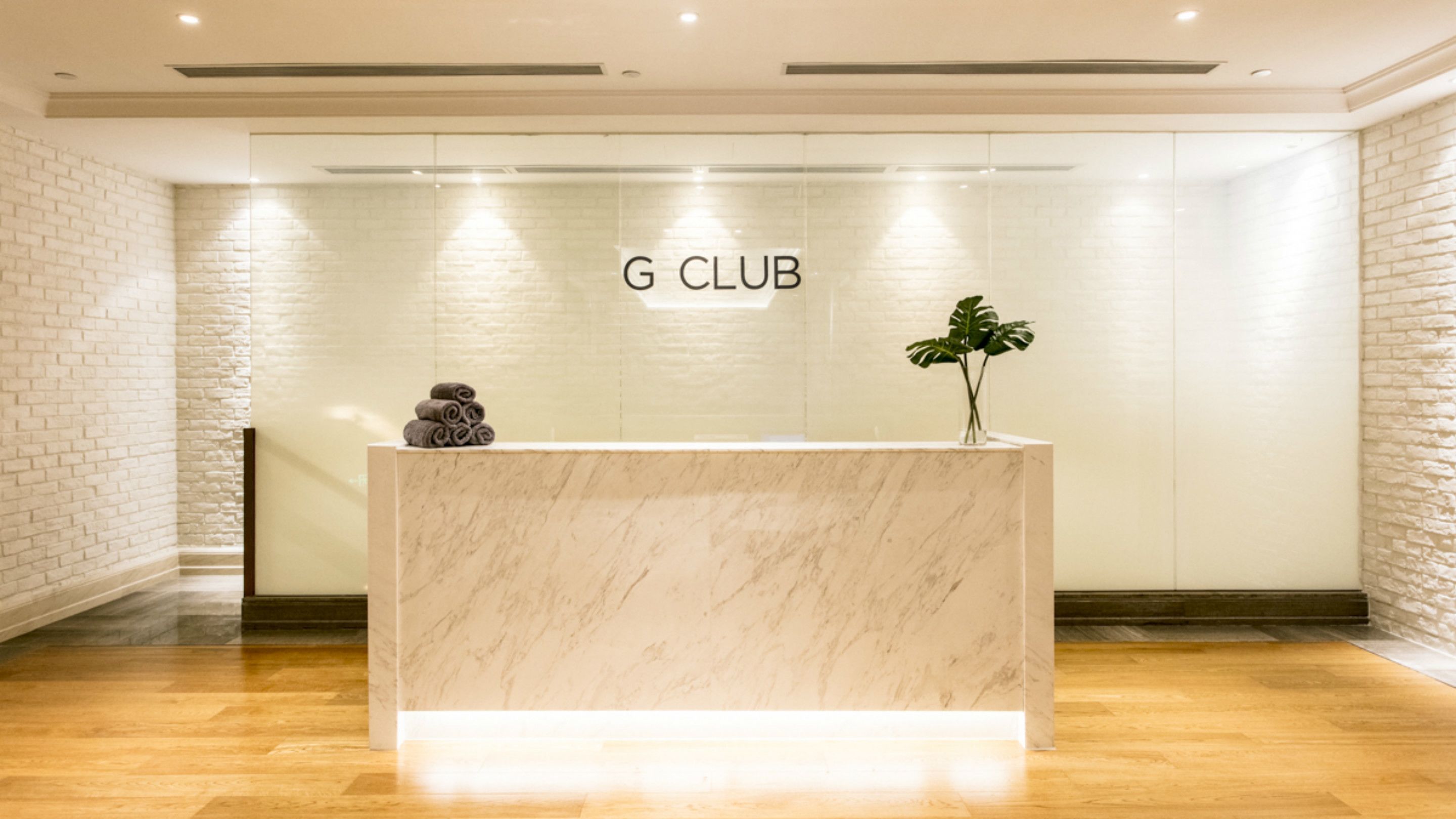 A reception desk with a marble top, a 'G CLUB' sign above, and a plant on the right.