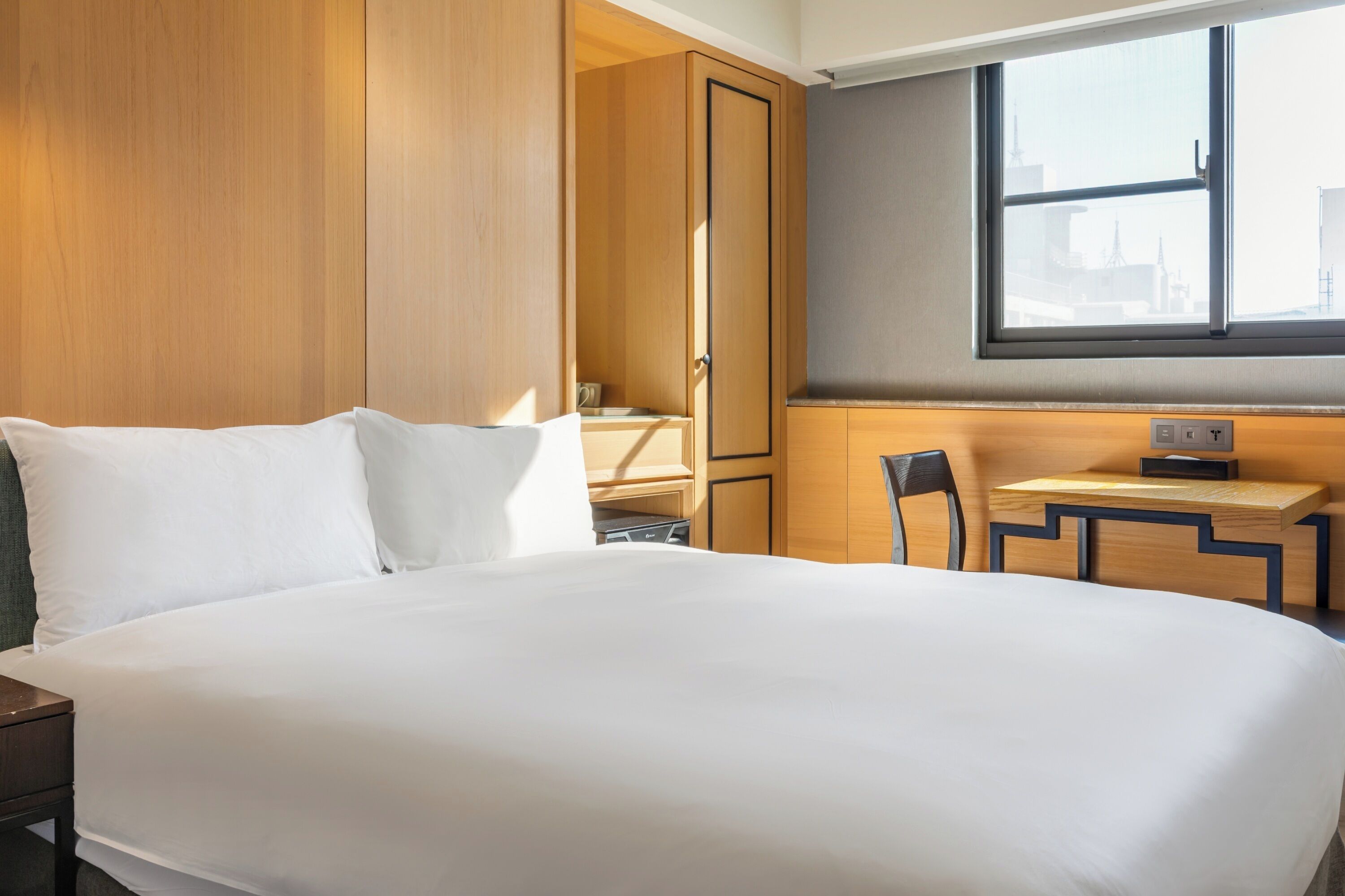 Et hotelværelse med en stor seng, et skrivebord og et klædeskab.