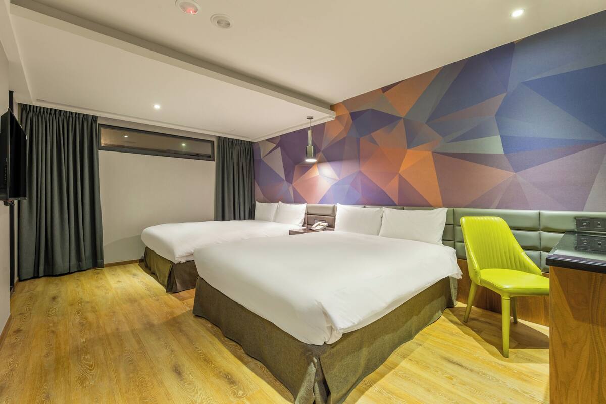 A hotel room with a large bed, a desk, and a green chair.