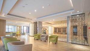 Um hall amplo com assentos modernos, uma área de recepção e uma parede decorativa.