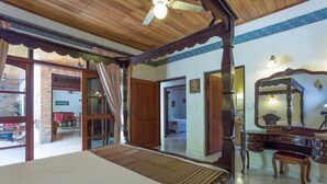 Ein Schlafzimmer mit Himmelbett, Holzboden und einem großen Spiegel.