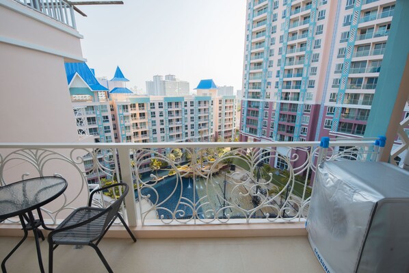 Un balcon avec vue sur des immeubles de grande hauteur, une piscine et un espace abrité.
