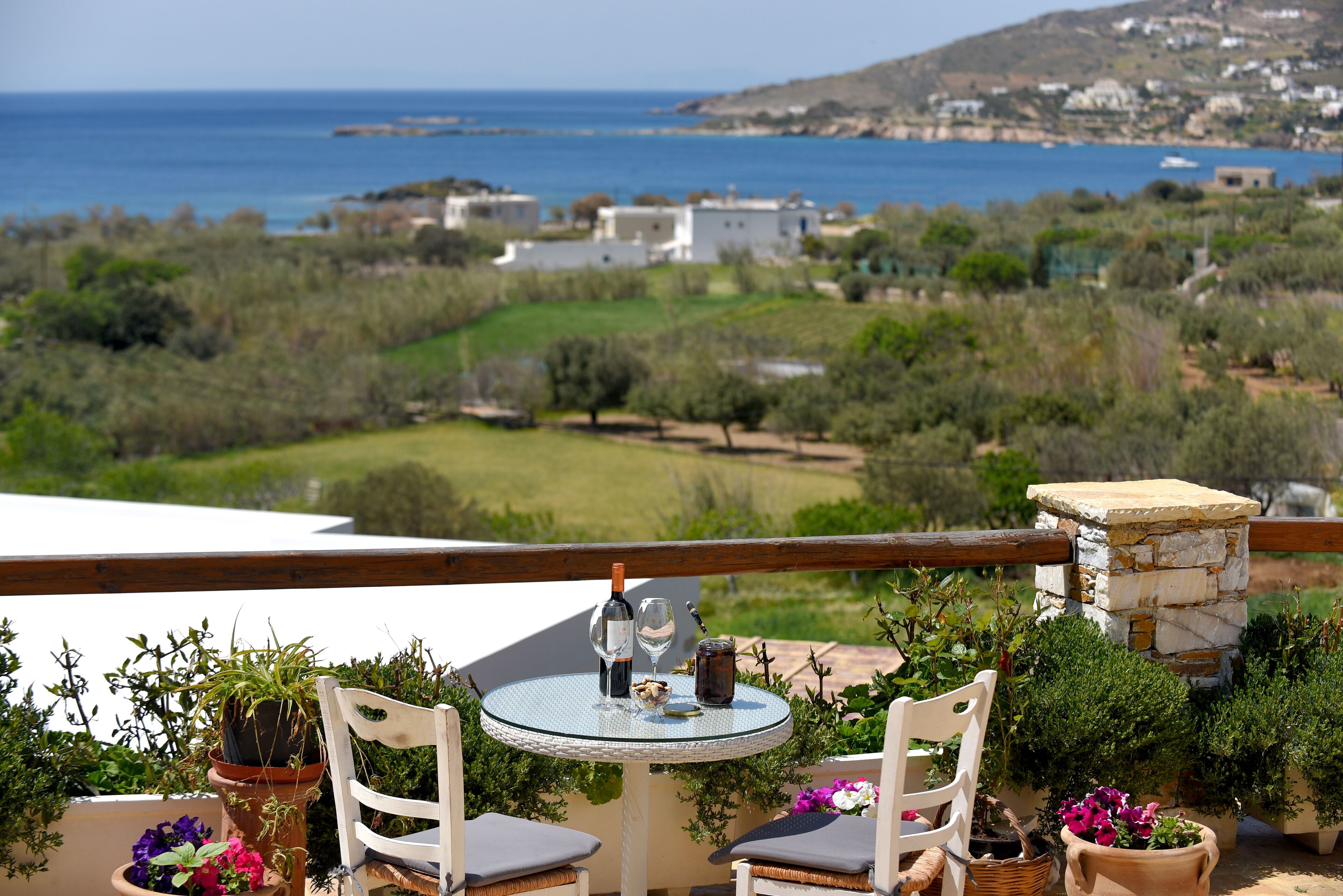 Eine Terrasse mit rundem Tisch, zwei Stühlen und Blick auf Meer und Landschaft.