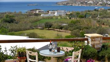 Eine Terrasse mit rundem Tisch, zwei Stühlen und Blick auf Meer und Landschaft.