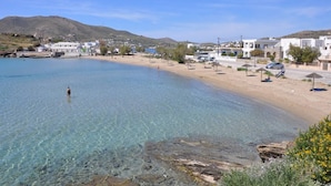 Un pueblo costero con aguas cristalinas, playa de arena y edificios blancos.