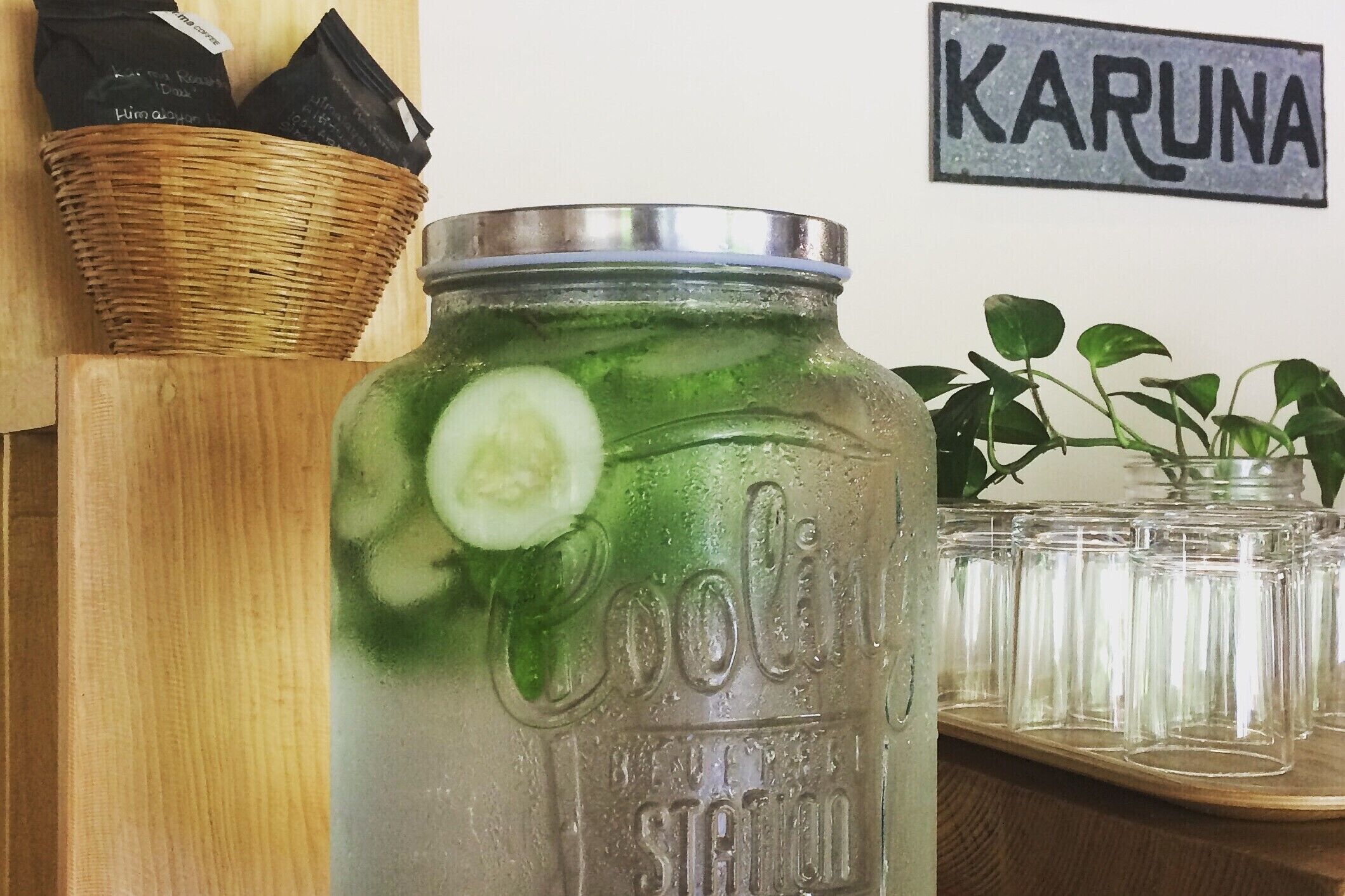 Un barattolo di vetro con coperchio metallico, contenente un liquido verde e fette di cetriolo, etichettato 'Coolin' e 'Beverly Station'.
