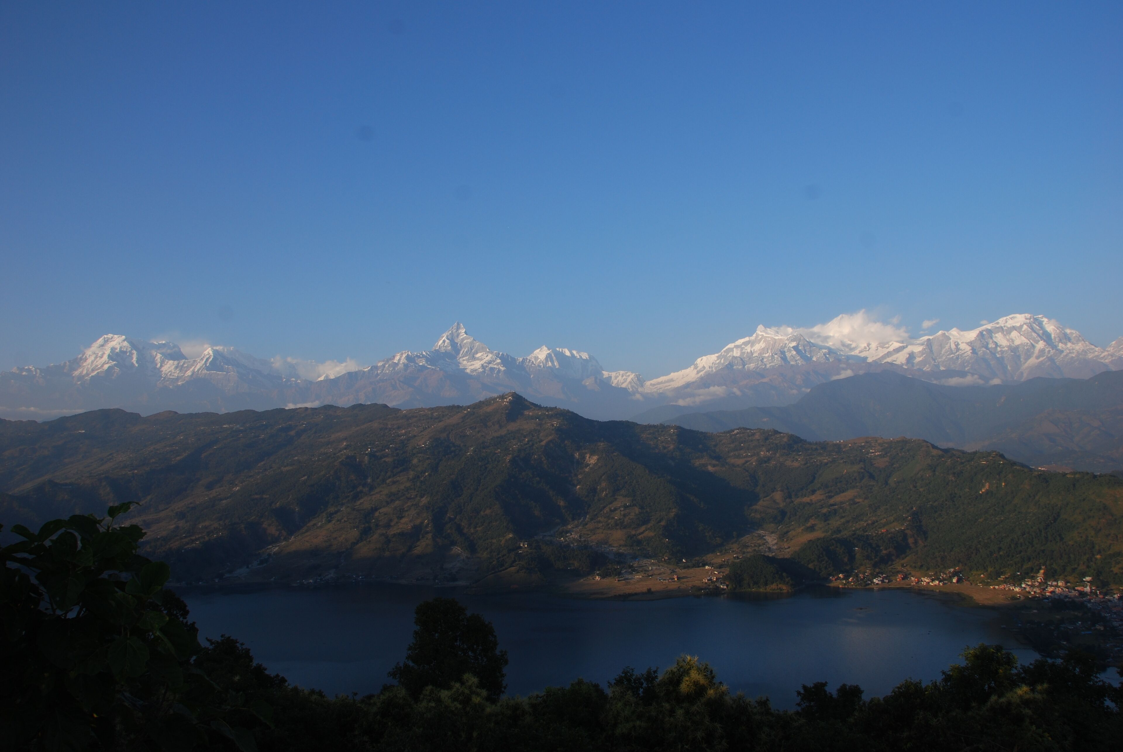 A mountainous landscape with a lake and snow-capped peaks in the background.