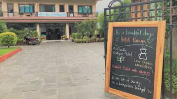A hotel entrance with a signboard advertising a breakfast buffet with waffles and local organic coffee.