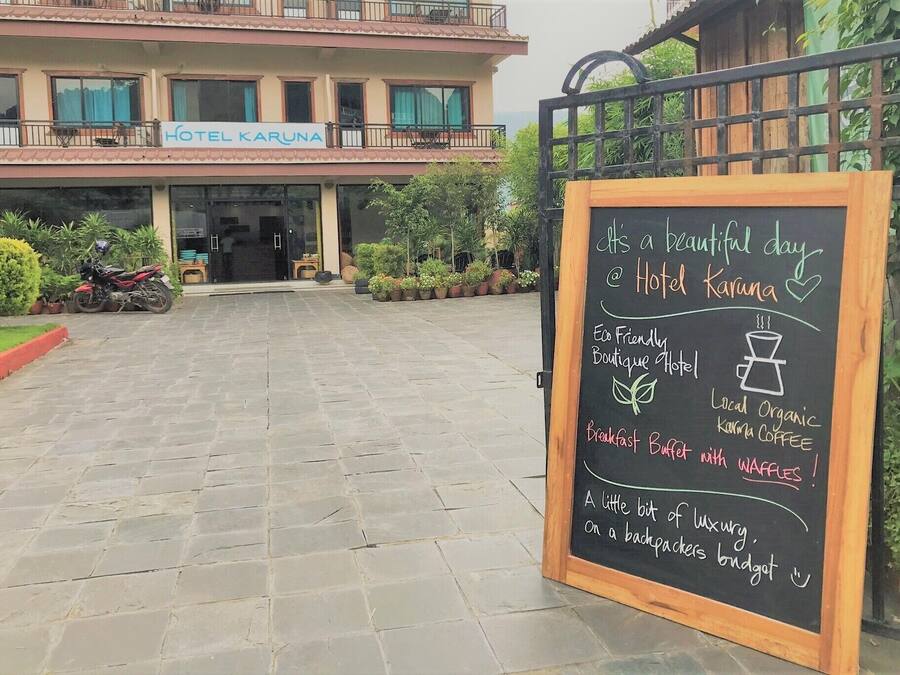 A hotel entrance with a signboard advertising a breakfast buffet with waffles and local organic coffee.
