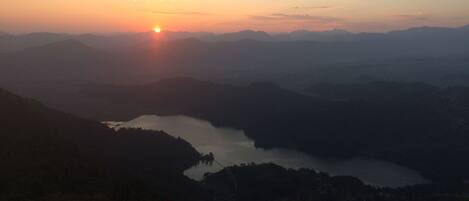 A mountain landscape with a lake and a sunset.