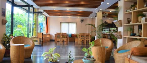 Un hall d’entrée spacieux, doté d’un plancher en bois, de meubles en osier et de plantes en pot.