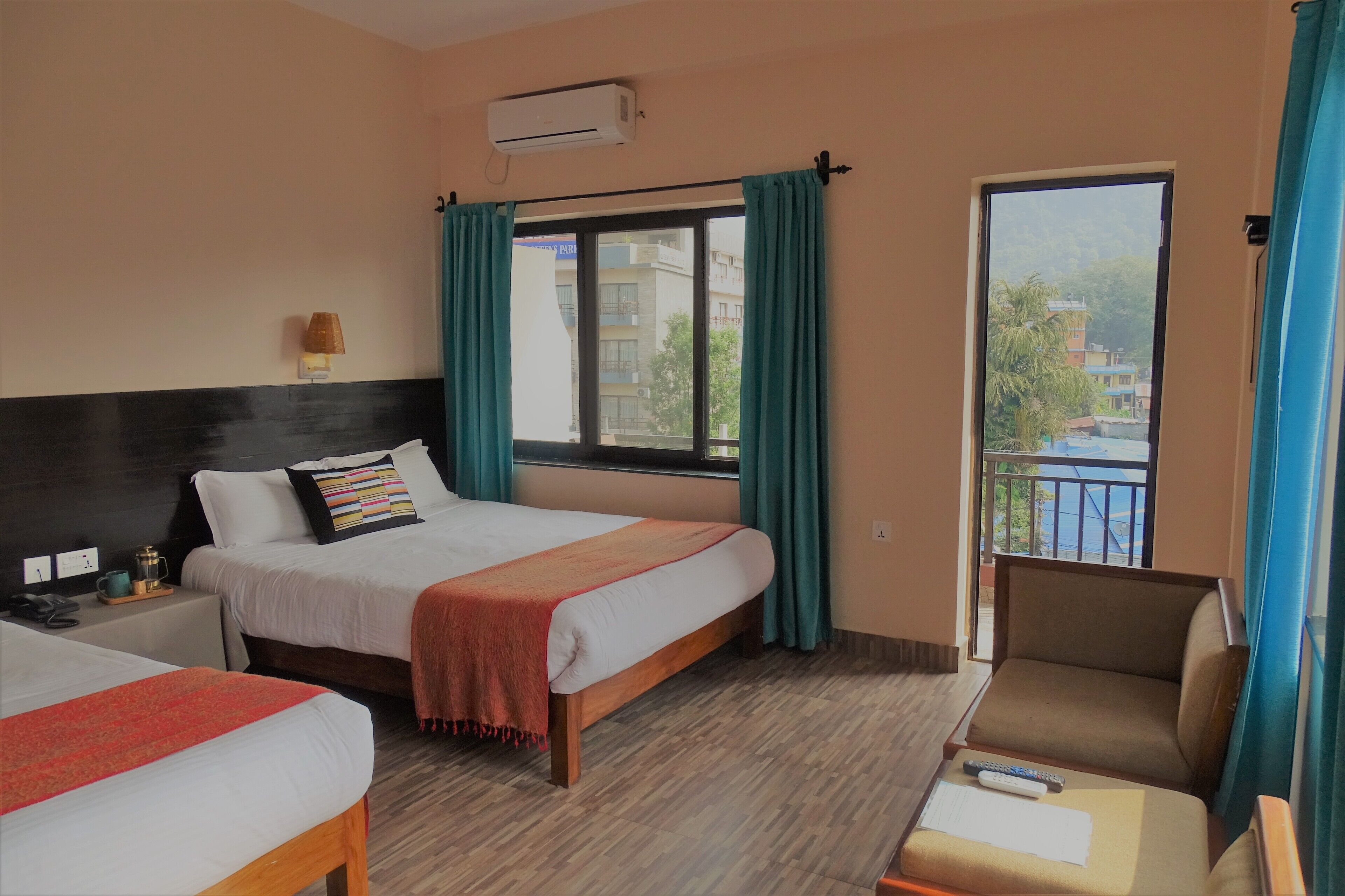 Ein Hotelzimmer mit Bett, Sessel, Schreibtisch und einem fenster mit Vorhängen.