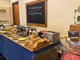 Un bufé de desayuno con diversas opciones de comida y una pizarra con un mensaje.