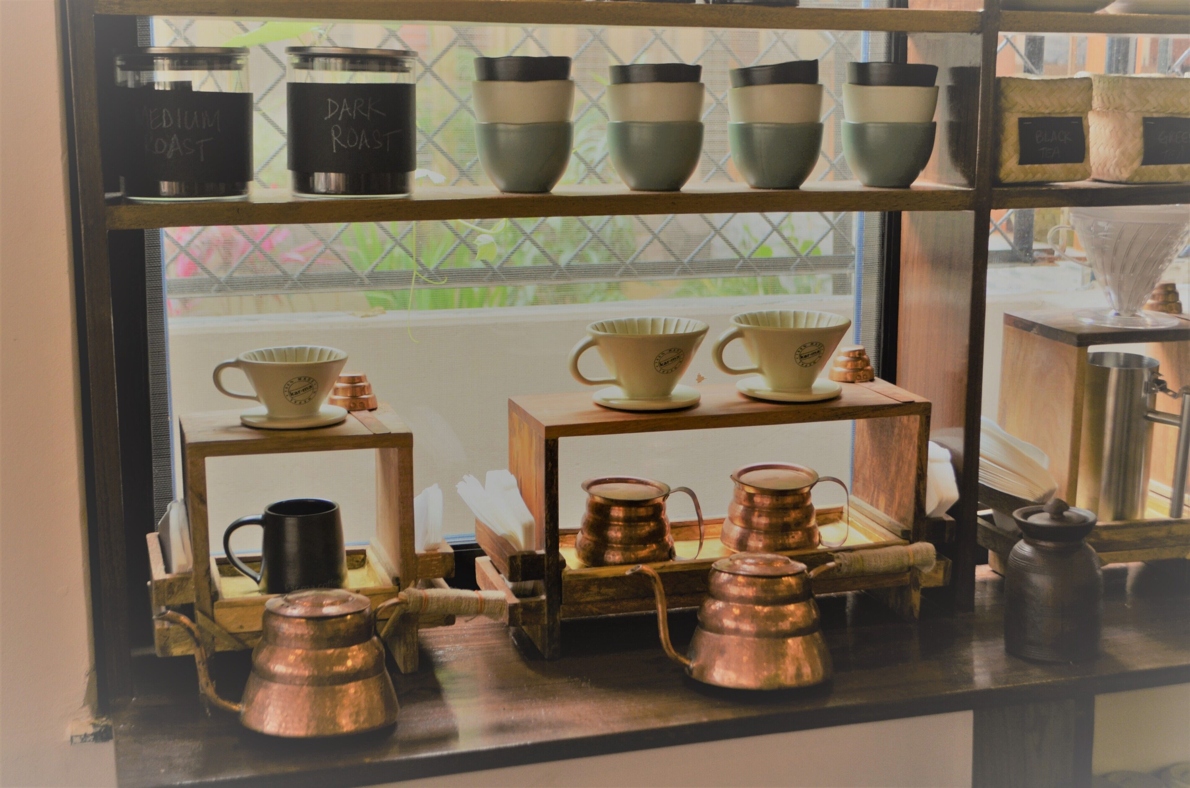 Una exhibición de utensilios de cocina que incluye tazas, vasos y teteras sobre estantes.