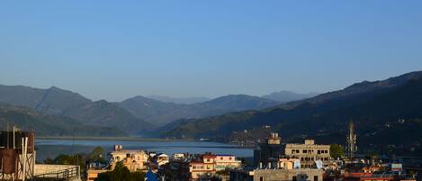 A coastal town with buildings along the waterfront, a clear view of the sea, and mountains in the background.