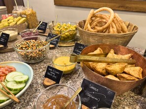 A buffet with various dishes including samosas, chutney, and a salad.