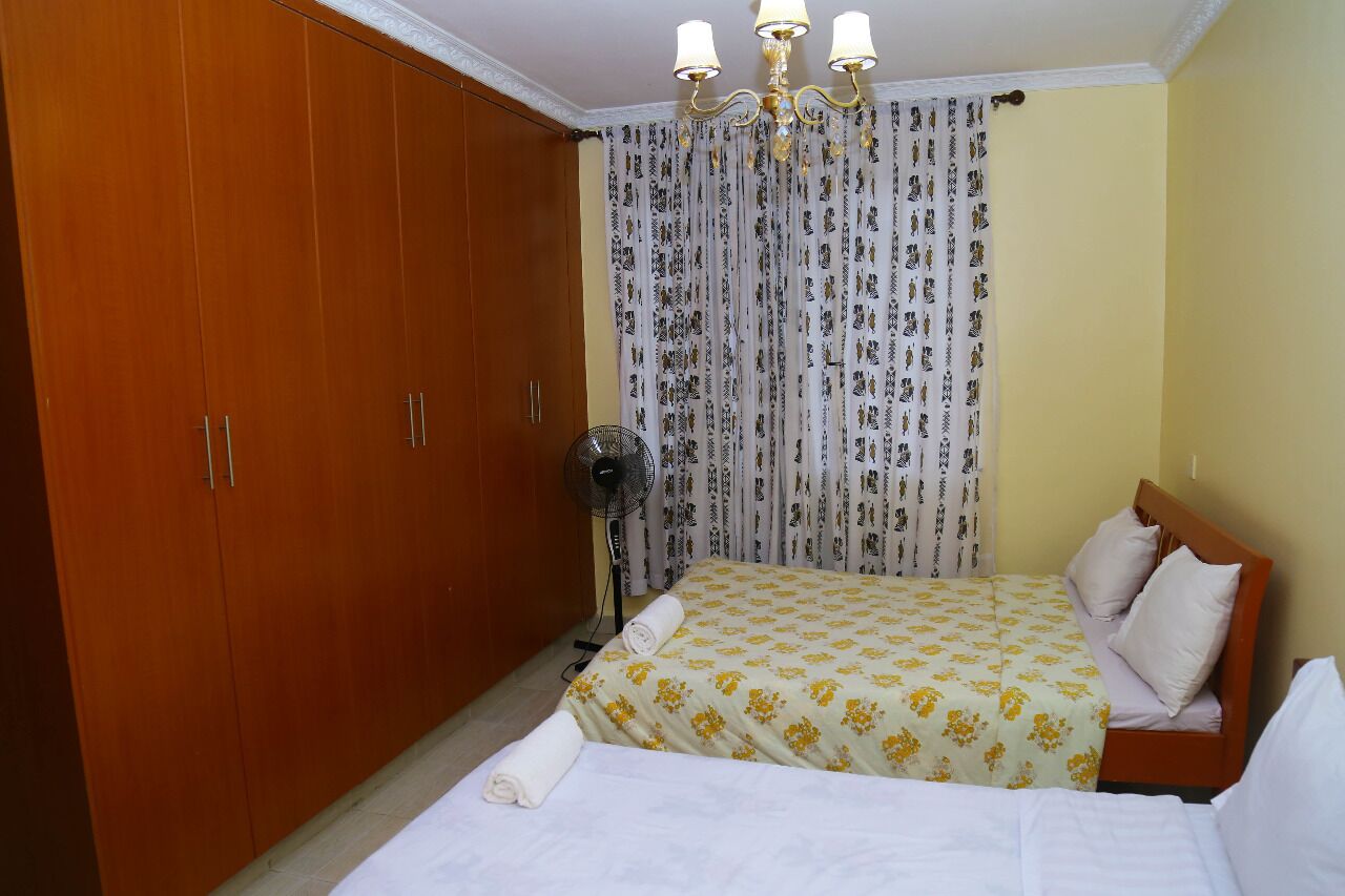 Une chambre à coucher avec un lit, un ventilateur, une armoire et un lustre.
