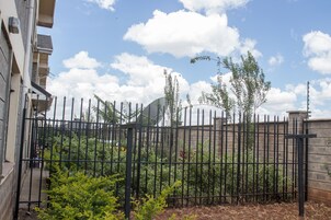 A gated area with a fence, a building, and some greenery.