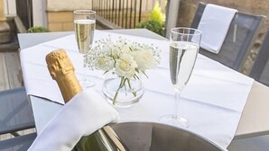 A table set for a meal with a bottle of champagne, a glass of water, and a vase with white flowers. - The Lane Hotel (Edinburgh)