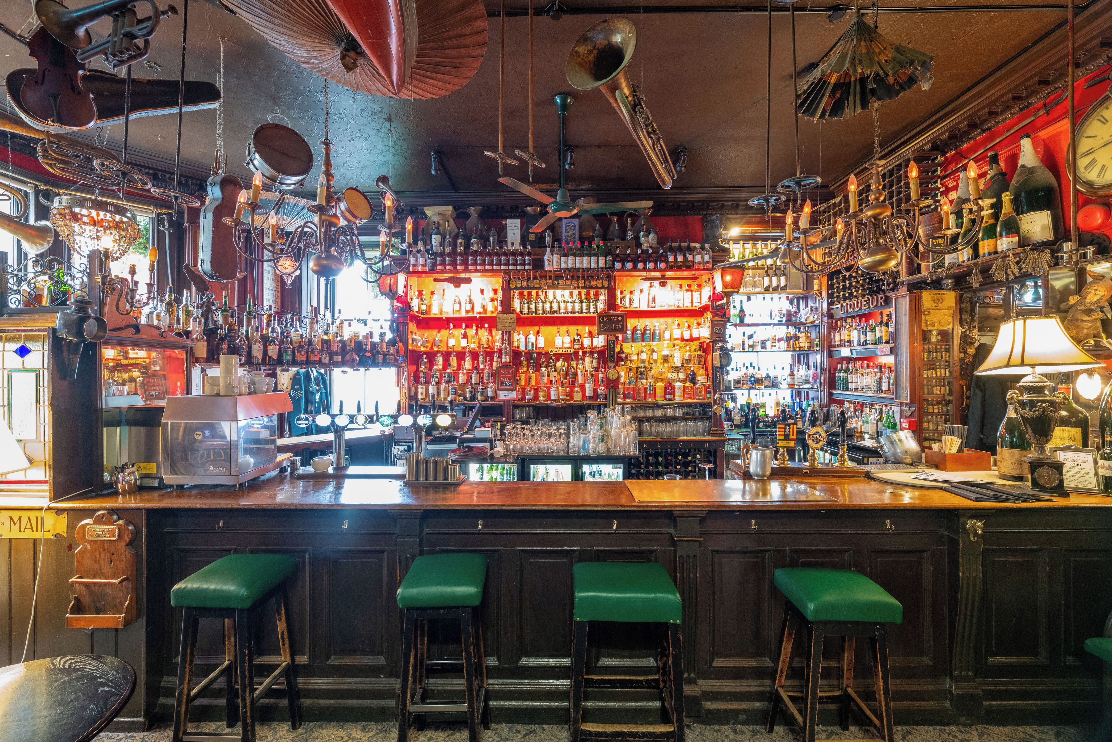 A bar with a variety of liquor bottles, a cash register, and stools.
