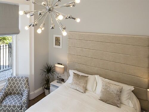 Une chambre à coucher avec un grand lit, une tête de lit, des tables de chevet, une lampe et une chaise.