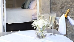 A room with a bed, a table with a vase of flowers, and a bottle of champagne. - The Lane Hotel (Edinburgh)