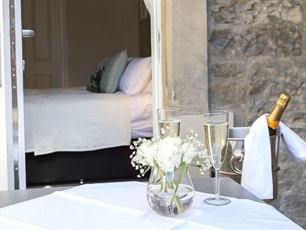 A room with a bed, a table with a vase of flowers, and a bottle of champagne. - The Lane Hotel (Edinburgh)