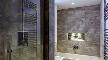 A modern bathroom with a glass shower enclosure, a built-in sink, and a wall-mounted mirror.