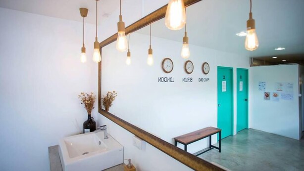 A modern bathroom with a large mirror, pendant lights, a sink, and a bench. - Hello Hostel Pakchong (Pak Chong)