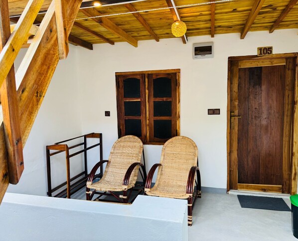 Um quarto com duas cadeiras de vime, uma porta de madeira e uma janela com moldura de madeira.