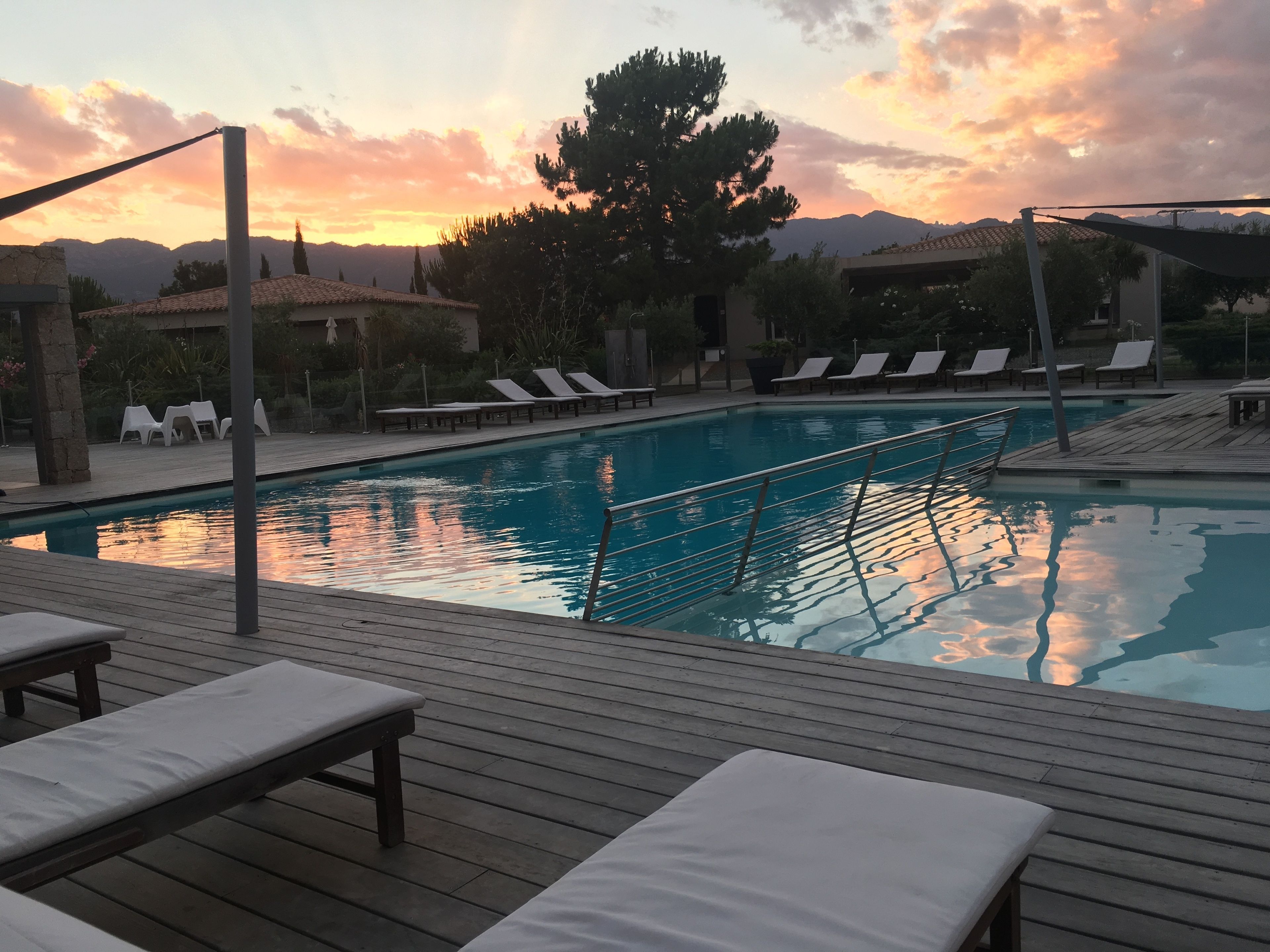 A swimming pool with lounge chairs and a wooden deck.