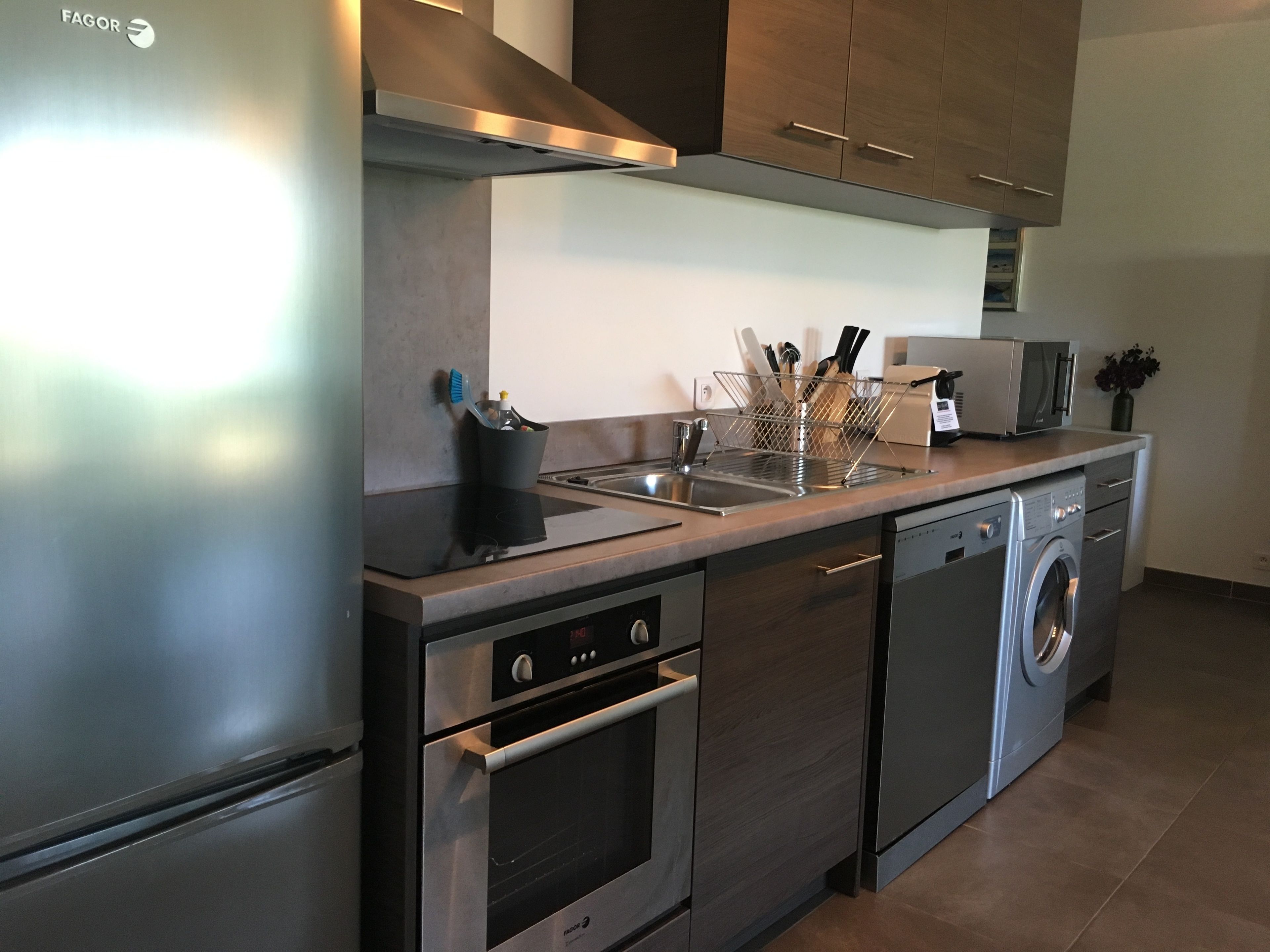 A modern kitchen with stainless steel appliances, including a refrigerator, oven, and dishwasher.